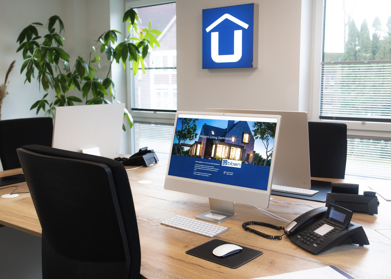 Büro von Ubben Immobilien mit Arbeitsplätzen und Logo an der Wand