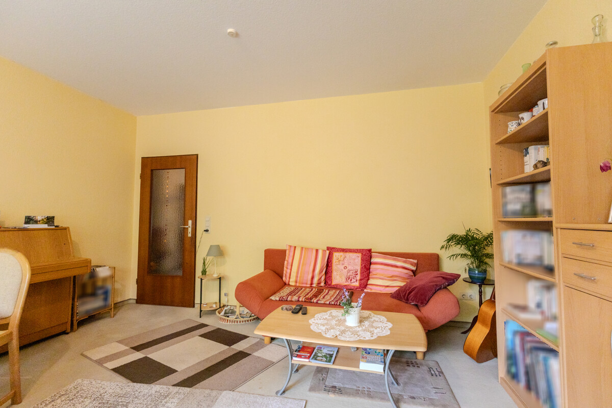 Wohnzimmer mit Sofa und Regalwand der vermieteten Erdgeschosswohnung in Aurich