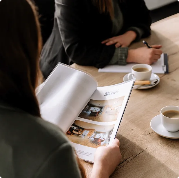 Beratungsgespräch mit Exposé und Kaffee am Tisch